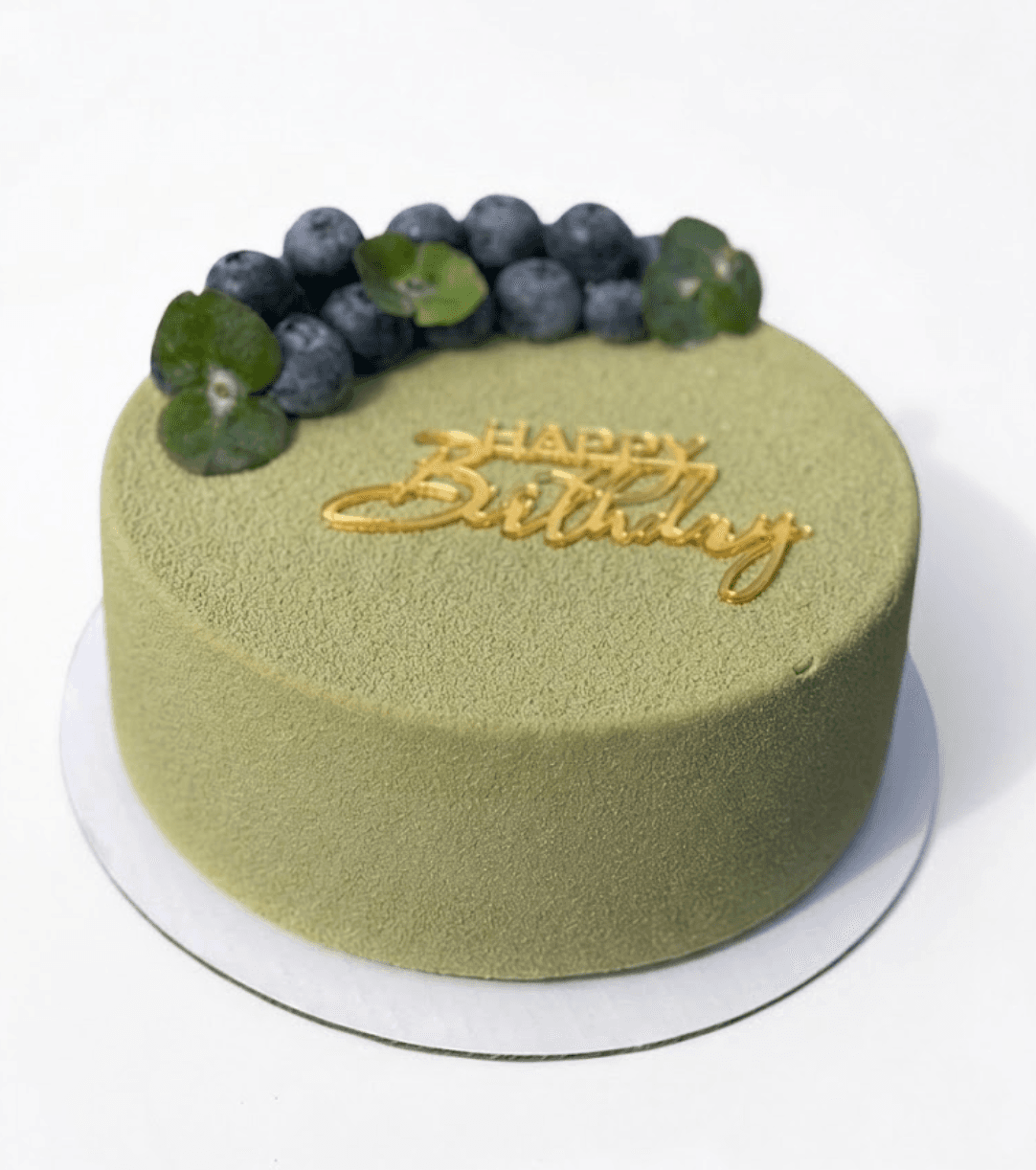 Pistachio birthday cake with blueberries and gold Happy Birthday inscription