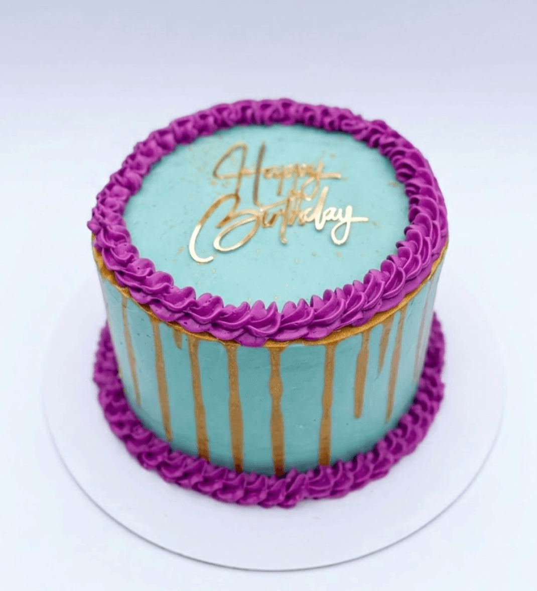 Turquoise birthday cake with purple cream border and gold drip decoration